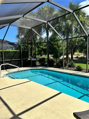 Swimming pool with a patio area, glass enclosure, and a grill