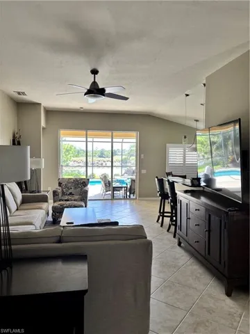 Living room with light tile patterned flooring, lofted ceiling, and a ceiling fan