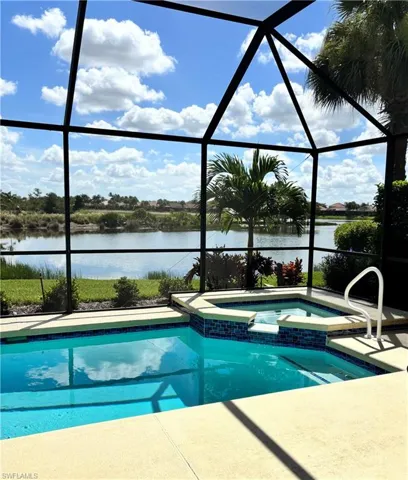 View of swimming pool with a water view, a pool with connected hot tub, a lanai, and a patio area