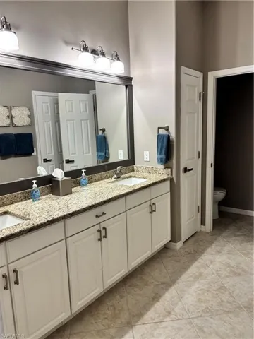 Full bath featuring double vanity and tile patterned flooring