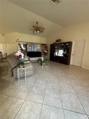 Unfurnished living room with vaulted ceiling, tile patterned floors, and ceiling fan