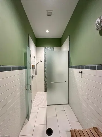 Bathroom featuring tile walls, tile patterned floors, and walk in shower