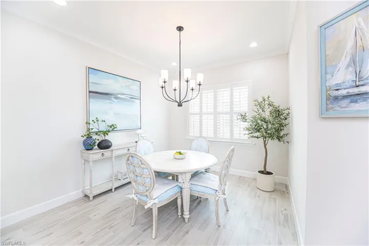 Dining area featuring ornamental molding, a notable chandelier, and light wood-type flooring