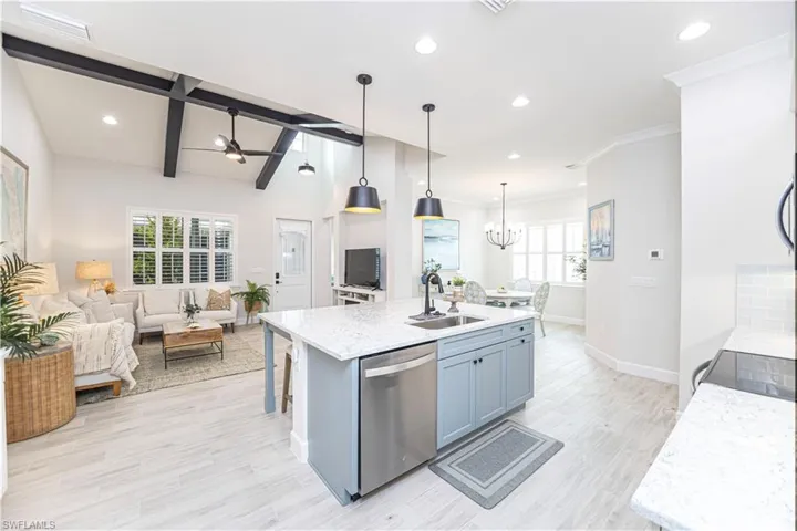 Kitchen featuring decorative light fixtures, dishwasher, an island with sink, sink, and light hardwood / wood-style floors