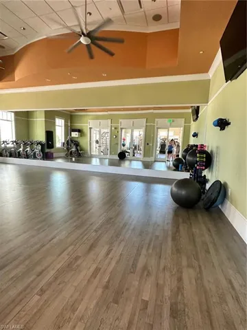 Workout area with hardwood / wood-style floors, ceiling fan, and a high ceiling