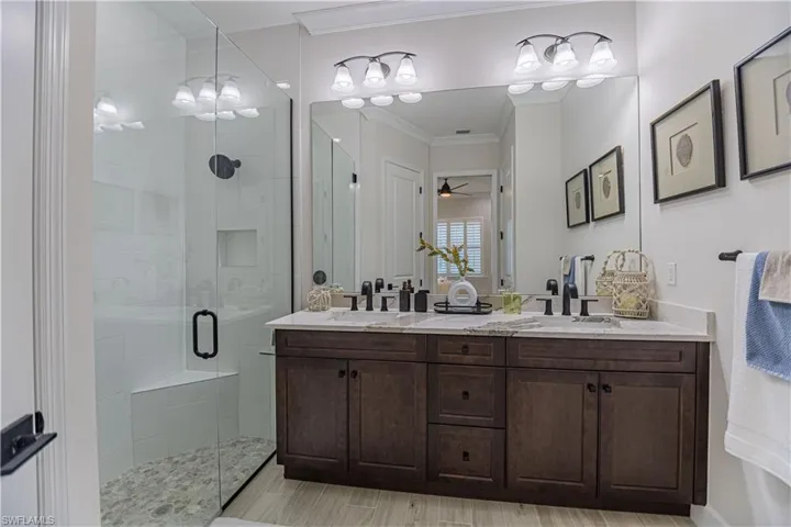 Bathroom with a shower with door, crown molding, vanity, and ceiling fan