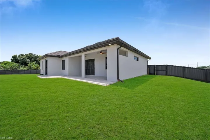 Back of property featuring a lawn, ceiling fan, and a patio