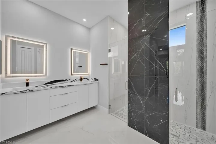 Bathroom featuring a shower with shower door and vanity