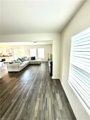 Spacious interior featuring wood-finish flooring, white baseboards, and neutral wall paint