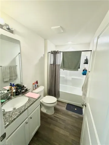 Bathroom featuring a white vanity with a speckled countertop, a drop-in sink, and white cabinetry