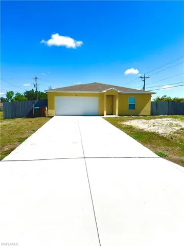 Single-story residence featuring a yellow exterior, an attached garage with a white door, and a brown shingle roof