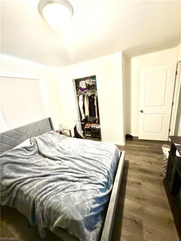 Bedroom featuring wood-finish flooring, white walls, and a recessed closet space