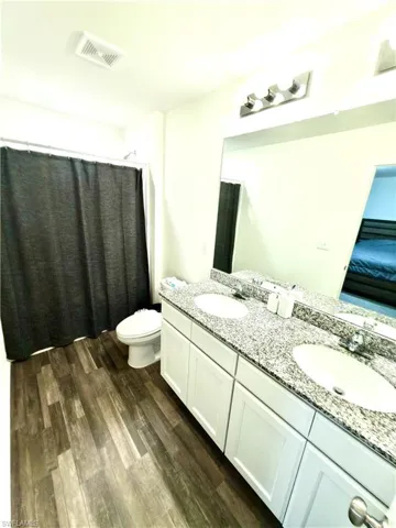 Double vanity with white cabinetry and speckled stone countertop