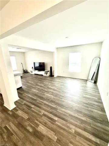 Open-concept living area featuring wood-finish flooring, white baseboards, and white walls