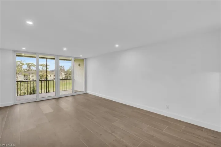 Unfurnished room with recessed lighting, light wood-type flooring, a residential view, and floor to ceiling windows