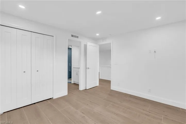 Unfurnished bedroom featuring recessed lighting, light wood-style flooring, a closet, and ensuite bathroom