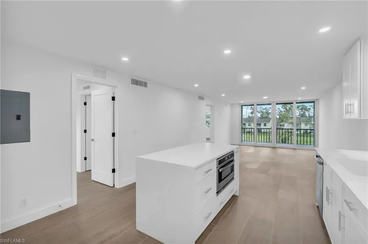 Kitchen featuring white cabinetry, recessed lighting, electric panel, light stone counters, and a kitchen island