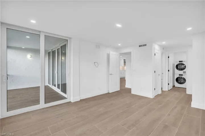 Empty room featuring recessed lighting, stacked washer / dryer, and light wood-style flooring