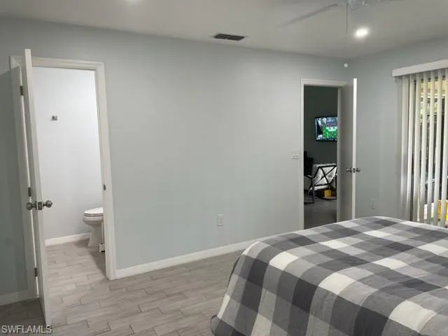 Bedroom featuring baseboards, light wood-type flooring, recessed lighting, ensuite bath, and a ceiling fan