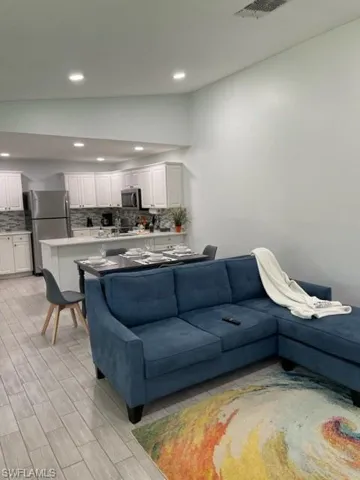 Living area featuring vaulted ceiling, recessed lighting, and light wood-style floors