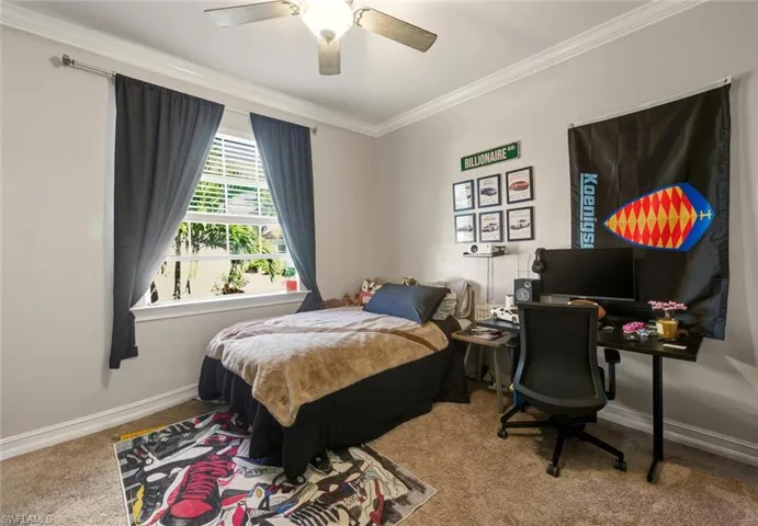 Bedroom featuring light colored carpet, ornamental molding, a ceiling fan, and an office area