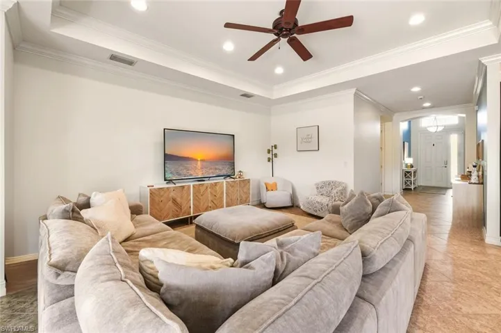 Living area featuring a raised ceiling, recessed lighting, ornamental molding, and a ceiling fan