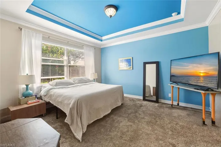 Carpeted bedroom featuring a tray ceiling and ornamental molding