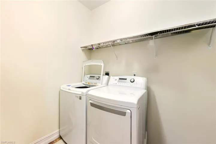 Washroom featuring washing machine and dryer and baseboards