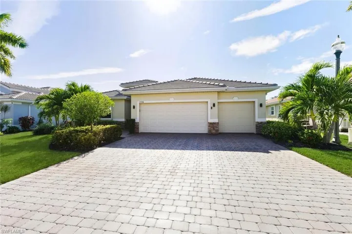 View of front of property featuring stone siding, decorative driveway, a garage, and stucco siding