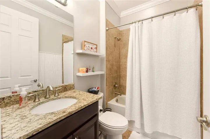 Full bathroom with ornamental molding, vanity, and shower / bathtub combination with curtain