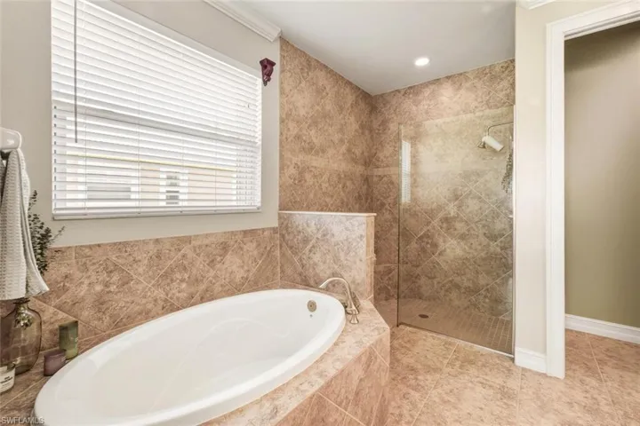 Bathroom with a bath, a stall shower, recessed lighting, light tile patterned flooring, and crown molding