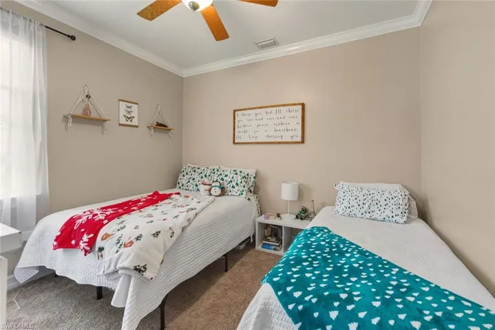 Carpeted bedroom with ornamental molding, multiple windows, and ceiling fan