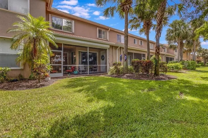 Rear view of house with a yard and screened in lanai