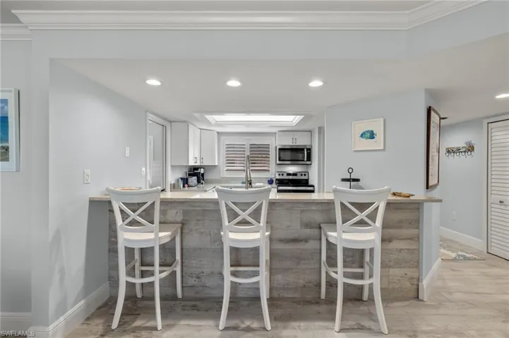 Kitchen featuring stove, white cabinets, ornamental molding, light hardwood / wood-style floors, and kitchen peninsula