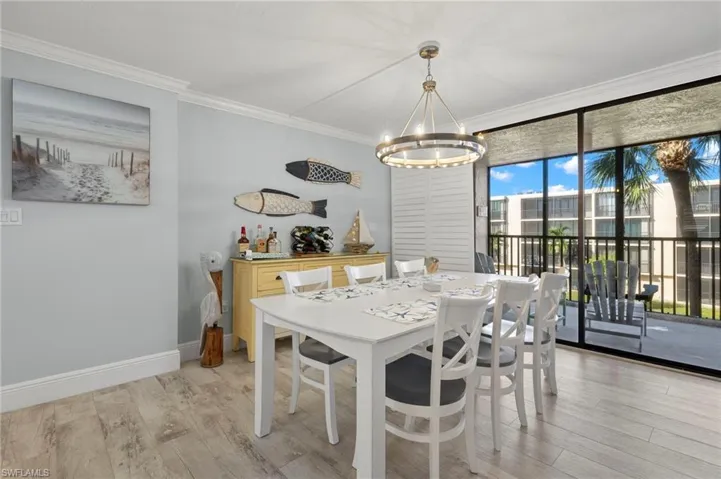 Dining room featuring light wood-type flooring, crown molding, and a chandelier