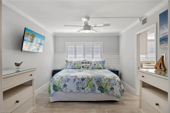 Bedroom featuring ceiling fan, light hardwood / wood-style floors, and crown molding