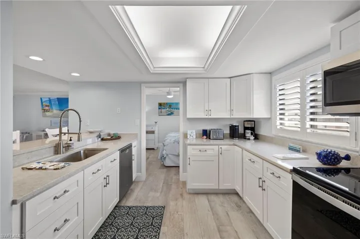 Kitchen featuring appliances with stainless steel finishes, sink, light hardwood / wood-style floors, and white cabinetry