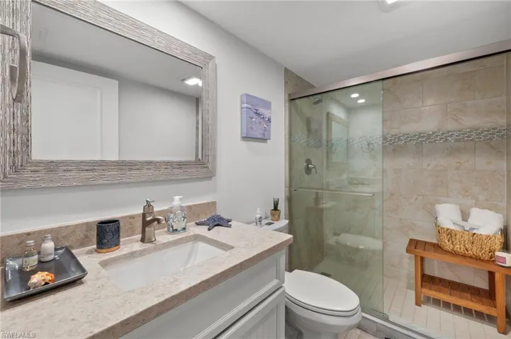 Bathroom featuring a shower with door, tile patterned flooring, vanity, and toilet