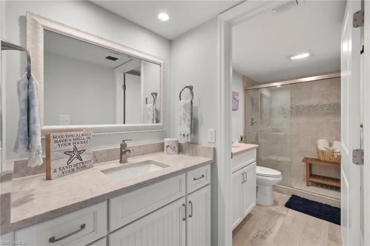 Bathroom featuring tile walls, toilet, vanity, and a shower with shower door