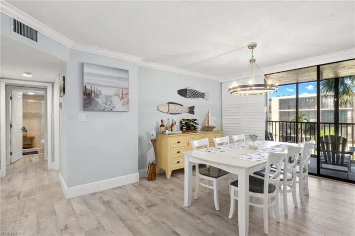 Dining space with a chandelier, light hardwood / wood-style floors, and crown molding