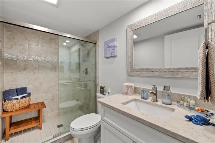 Bathroom featuring toilet, vanity, and a shower with shower door
