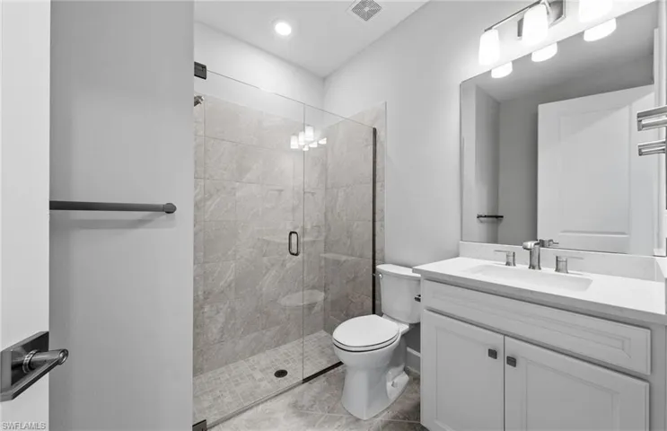 Bathroom with a shower with door, toilet, vanity, and tile patterned floors