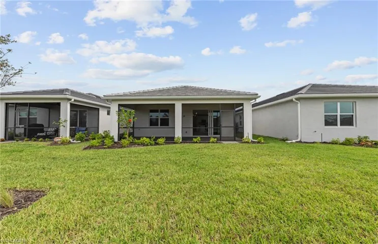 Rear view of property with a sunroom and a lawn