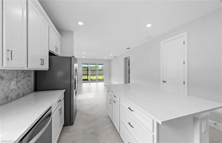 Kitchen with backsplash, white cabinetry, dishwasher, a center island, and light stone countertops