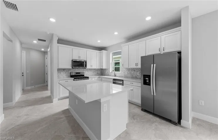 Kitchen with a center island, sink, white cabinets, stainless steel appliances, and backsplash