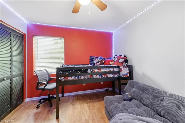 Room featuring wood-finish flooring, a ceiling fan, and a window with horizontal blinds