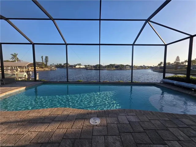 Swimming pool featuring a sunroom, a water view, and glass enclosure