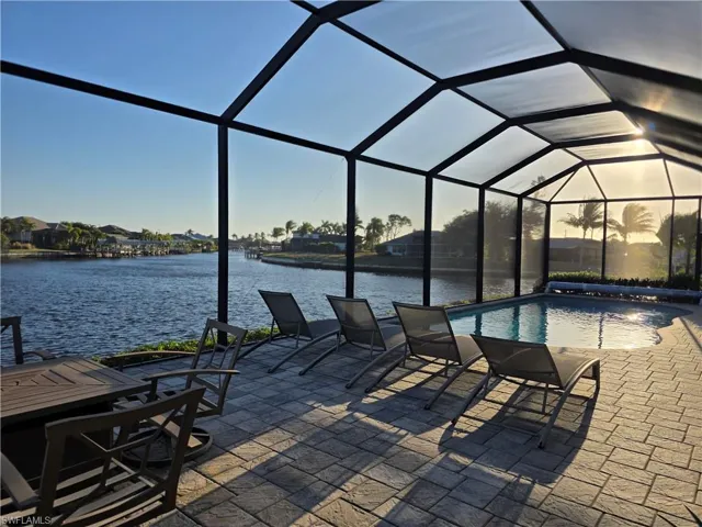 View of patio with a sunroom, a lanai, an outdoor pool, and a water view
