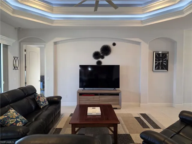 Tiled living room featuring crown molding and a raised ceiling