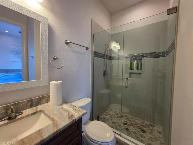 Full bathroom / Pool Bath featuring a textured wall, vanity, and a stall shower